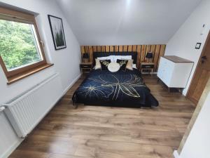 a bedroom with a bed with a wooden floor at DOMEK NA GÓRACH z JACUZZI I SAUNĄ in Nowy Sącz