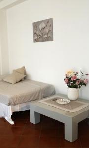 una habitación con una cama y una mesa con un jarrón de flores en BlancoHouse Viale Ceccarini, en Riccione