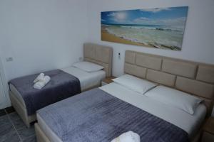 Fishta apartments Q5 32 في فيليبوجي: غرفة نوم بسريرين وصورة للشاطئ