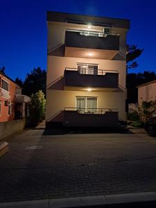 a white building with a balcony on the side of it at Apartmani Vukadin in Vir