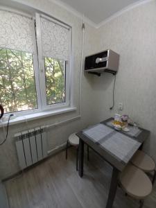 Zimmer mit einem Tisch, einem TV und 2 Fenstern in der Unterkunft ОРАНЖЕВЫЙ МИР in Aqtöbe
