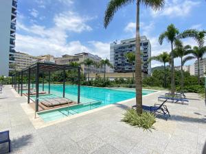 una piscina con sillas y palmeras en una ciudad en Apartamento moderno completo, en Río de Janeiro