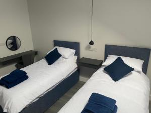 two beds in a room with blue pillows on them at Ballymullock Barn Lofts in Carncastle