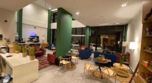 un vestíbulo con mesas y sillas y una columna verde en ريف سويت للأجنحة الفندقية en Abha