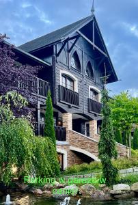 a black building with a balcony and a river at Dolina Wikingów-apartament Suite z tarasem w ogrodzie, miejscem w garażu i dostępem do strefy wellness in Szklarska Poręba