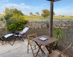 een tafel en stoelen naast een stenen muur bij Rifugio tra gli ulivi in Marina di Ragusa