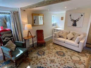 ein Wohnzimmer mit einem Sofa und einem Stuhl in der Unterkunft Beautiful cottage in country village near Longleat in Maiden Bradley