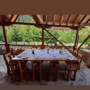 - une grande table en bois dans un pavillon avec des chaises et une table dans l'établissement Mulliri, à Peje