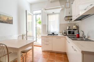 a kitchen with white cabinets and a table and a dining room at Queen House Venezia in Venice