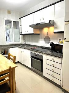 uma cozinha com armários brancos e bancadas pretas em Apartamento Praia Naval em Isla de Arosa