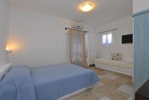 a bedroom with a blue bed and a couch at Degaetas Resort in Antiparos
