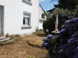 Casa blanca con mesa y flores púrpuras en Maison sur ferme maraichère bio, en Guiler-sur-Goyen