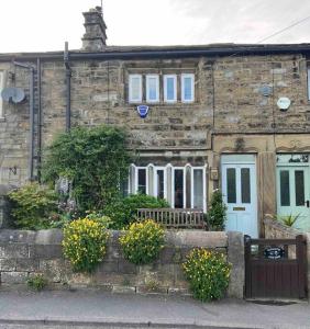 a stone house with a bench in front of it at 17th Century Cottage with Hidden Garden in Steeton