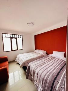 1 dormitorio con 2 camas y pared roja en Castellares la Puebla Hostelería Departamento en Ayacucho