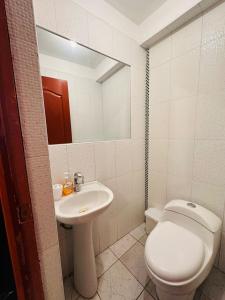 a bathroom with a sink and a toilet and a mirror at Castellares la Puebla Hostelería Departamento in Ayacucho