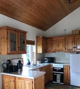 a kitchen with wooden cabinets and a white refrigerator at Kilronan Cottage in Ballyconneely