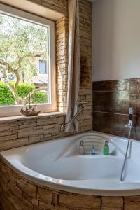 a bath tub in a bathroom with a window at Apartments Villa Sotlar with pool in Umag