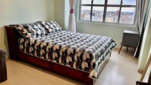 een slaapkamer met een bed met een geruite deken en een raam bij Curitiba Central - Apartamento completo e perto de tudo in Curitiba