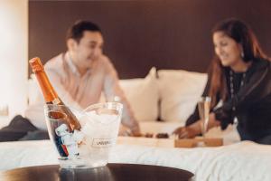 a man and woman sitting in a bed with a bottle of champagne at Four Points by Sheraton Santiago in Santiago