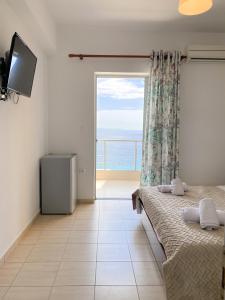 a bedroom with a large window with a view of the ocean at Acta's Rooms in Himare