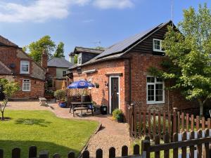 a brick house with a table and an umbrella at Hunston Mill Self Catering Dog Friendly in Chichester