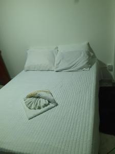 Una cama blanca con una cesta encima. en SUÍTE Princípio en Vila Velha