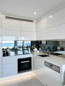 a kitchen with white cabinets and a sink at Bondi Beach Waves Beachfront Apartment in Sydney