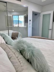 a bedroom with a bed with white sheets and a mirror at Bondi Beach Waves Beachfront Apartment in Sydney