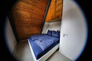 Dormitorio pequeño con cama azul y pared de madera en Chalet Alba, en Lichtenberg