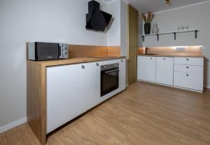 eine Küche mit weißen Schränken und einer Mikrowelle in der Unterkunft Design & Relax #Altstadt #Sauna in Lutherstadt Wittenberg