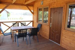 a wooden cabin with a table and chairs on a deck at Domek letniskowy w Karwiku in Karwik