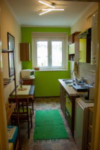 a green kitchen with a table and a window at Foxy Apartman in Eger