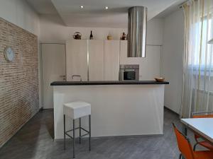 une cuisine avec des placards blancs et un comptoir avec un tabouret dans l'établissement CASA MATTIA, à Livourne