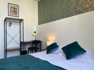 a bedroom with a large bed with two green pillows at Hotel TULTY in Tours