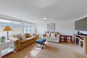 a living room with two couches and a tv at Grand Pacific in Rockaway Beach