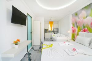 a white hotel room with a white bed and a tv at Suites El Greco in Potos