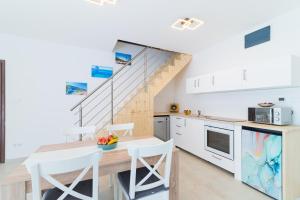 a kitchen with white cabinets and a wooden table with chairs at Eternity Apartmanház in Keszthely