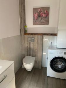 a bathroom with a toilet and a washing machine at Domek „Na Górkach” in Grybów