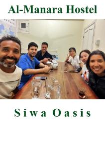 a group of people sitting around a wooden table at Al-Manara Hostel Siwa Oasis in Siwa