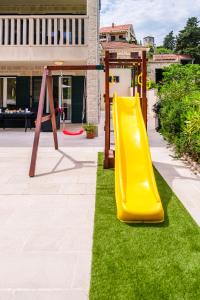 a playground with a yellow slide in a yard at Villa Janie - Luxury Multi-Level Estate with Pool in Supetar +56 photos