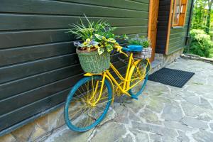 żółty rower zaparkowany obok domu z roślinami w obiekcie Family Relax & Willa Widok w Szczyrku