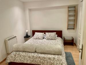 a bedroom with a bed with a brown headboard and pillows at Acogedor Dúplex Barrio del Pilar in Madrid