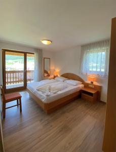 - une chambre avec un grand lit et un balcon dans l'établissement Apartments Stoll, à Valle Di Casies