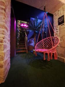 a swing hanging from a wall in a room at La Bayeuzen - La Tropicale - Love Room in Bayeux