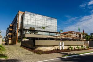 um grande edifício de vidro com guarda-chuvas em frente em Hardman Praia Hotel em João Pessoa