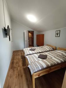 two beds in a small room with wooden floors at Tölgyfa Panzió in Balatonszepezd