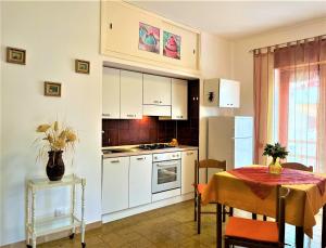 una cocina con armarios blancos y una mesa con mantel. en Casa MARINA en Scalea