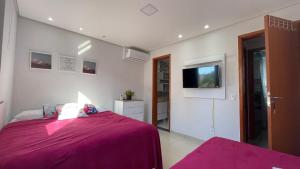 um quarto com uma cama roxa e uma televisão em Apt novo de alto padrão na melhor praia de Ilhéus em Ilhéus