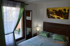 a bedroom with a bed with green pillows and a window at Preciosa casa con aparcamiento a 1km de la Toja in O Grove