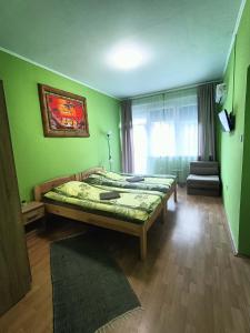 1 Schlafzimmer mit 2 Betten in einem Zimmer mit grünen Wänden in der Unterkunft Tölgyfa Panzió in Balatonszepezd